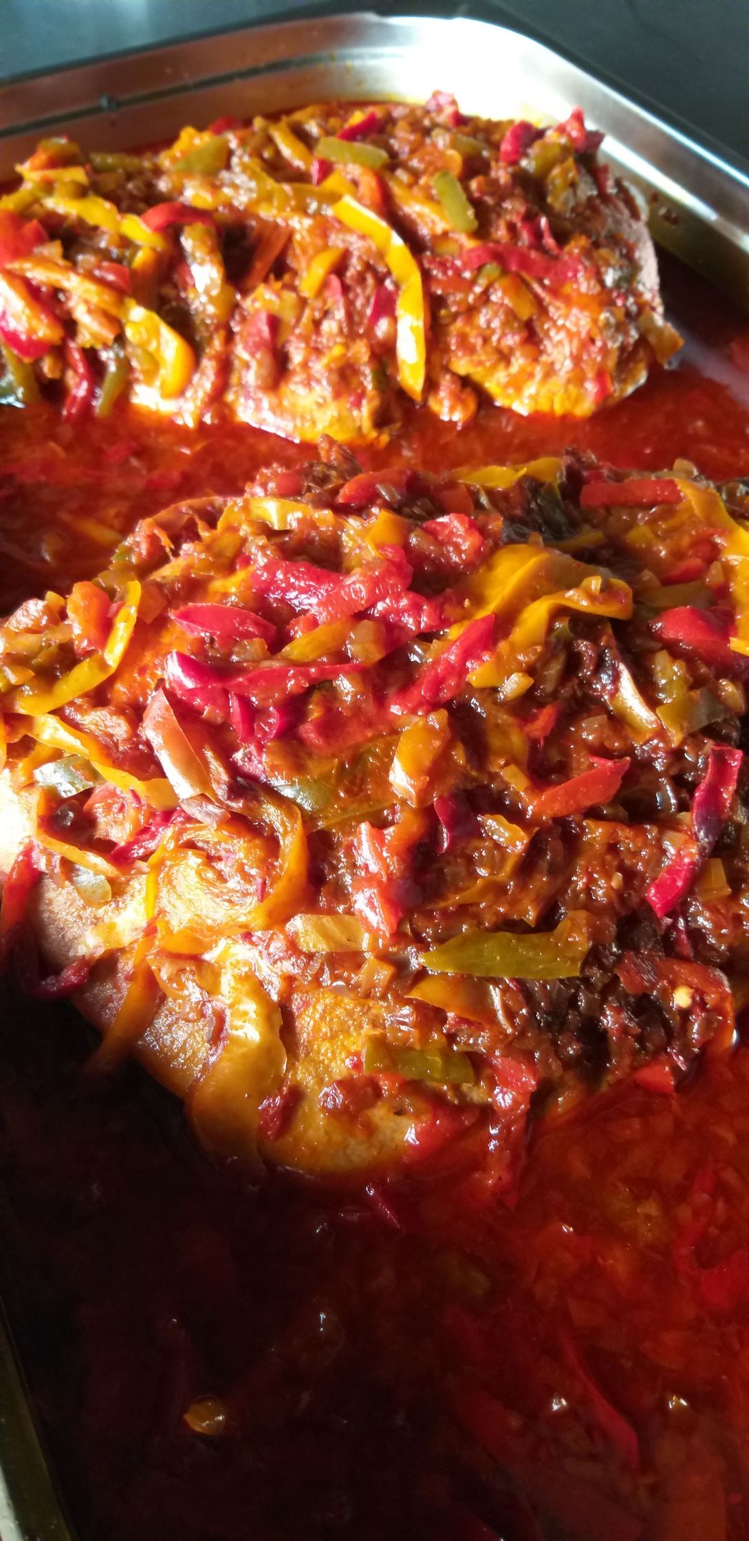 Eine Nahaufnahme einer Pfanne mit Essen, Tomatensoße und Paprika.