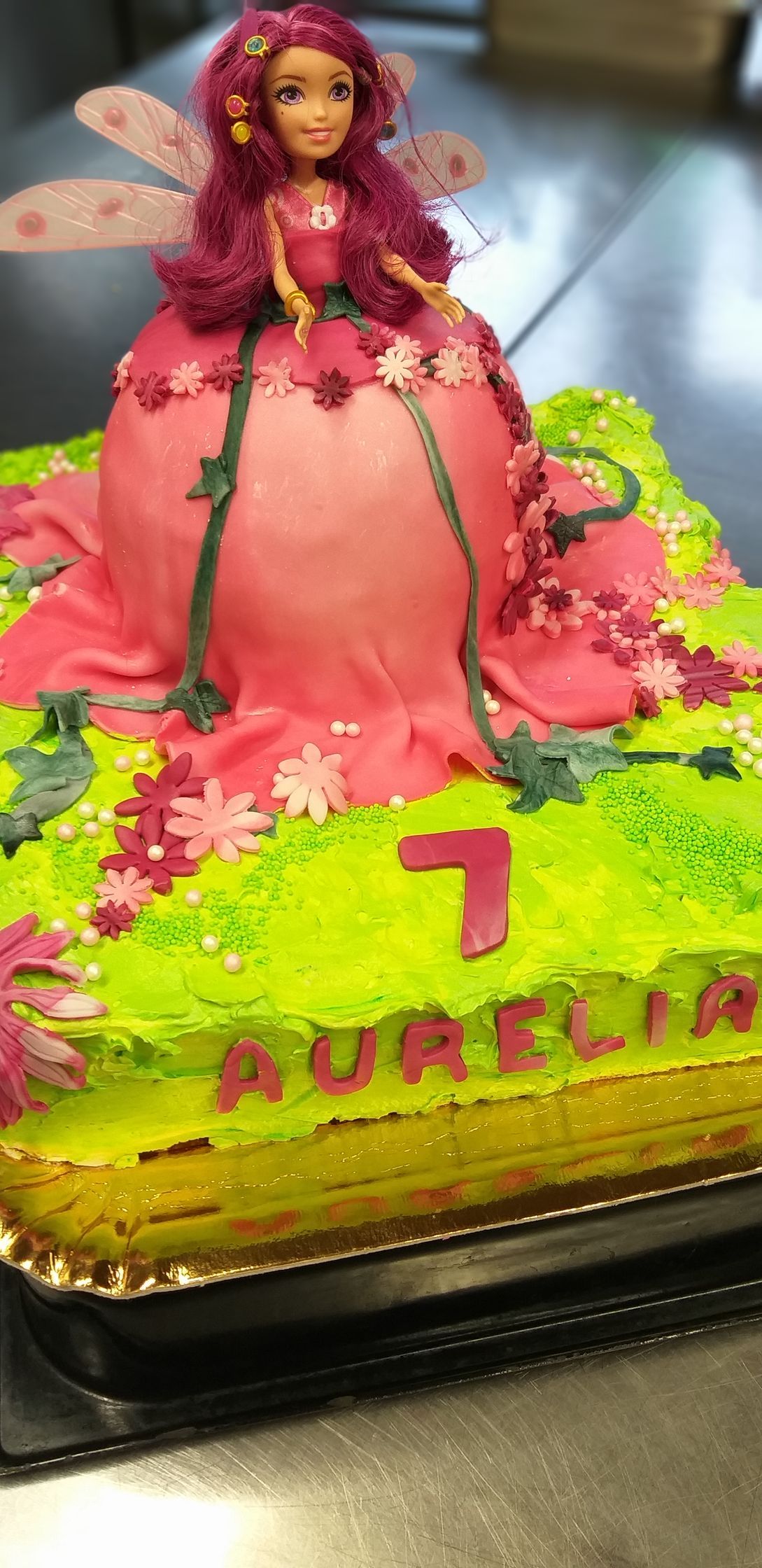 Eine Geburtstagstorte mit einer Feenpuppe obendrauf.