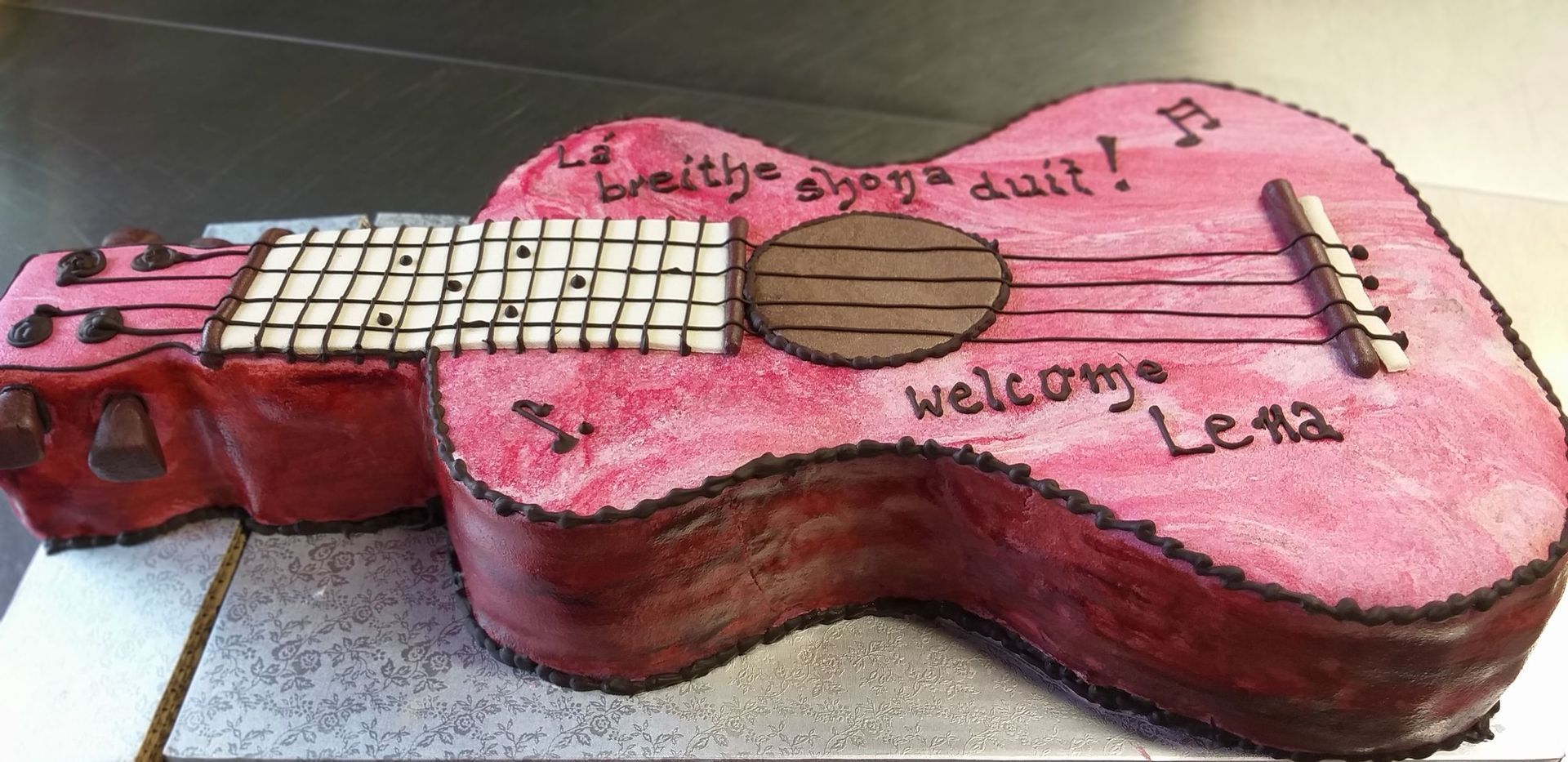 Auf einem Tisch steht ein Kuchen in Form einer Gitarre.