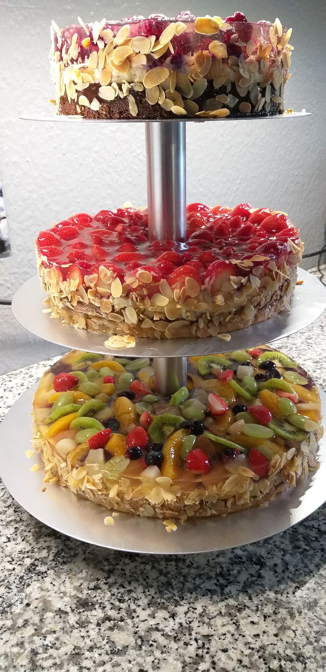 Auf einem Tortenständer sind drei Torten übereinander gestapelt.