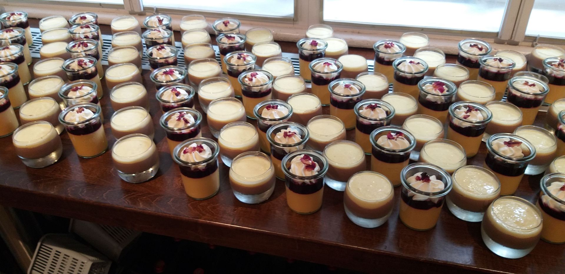 Ein Tisch mit vielen Schnapsgläsern voller Desserts.