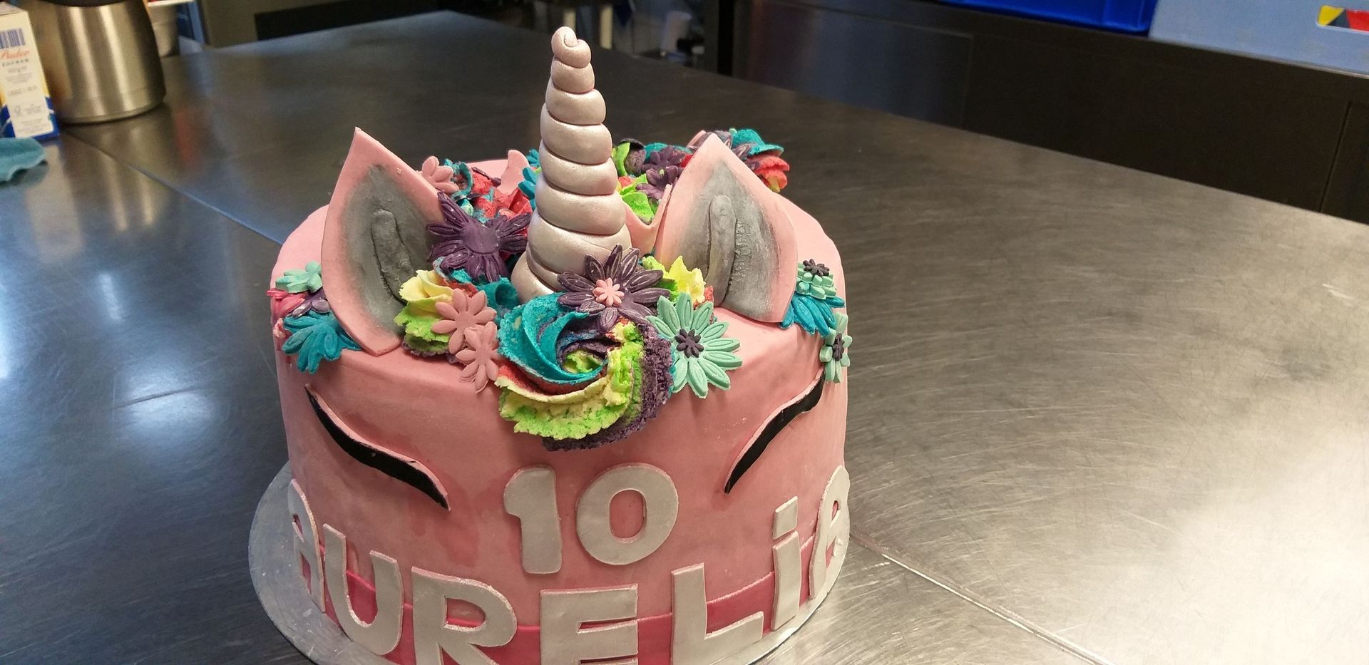 Auf einem Tisch steht ein rosa Einhornkuchen.