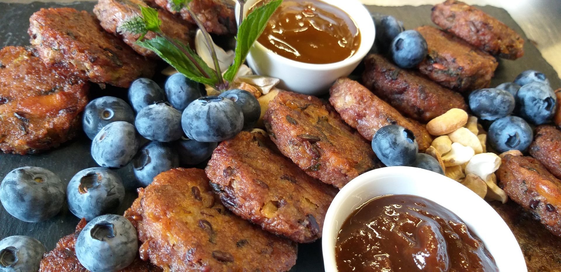 Ein Teller mit Essen, Blaubeeren und Soßen auf einem Tisch.