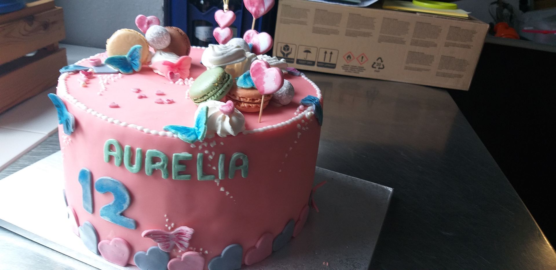 Auf einem Tisch steht ein rosa Kuchen mit dem Namen Aurelia darauf.