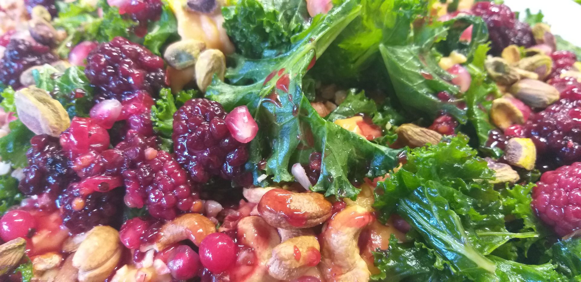 Eine Nahaufnahme eines Salats mit Grünkohl, Preiselbeeren, Pistazien und Nüssen.