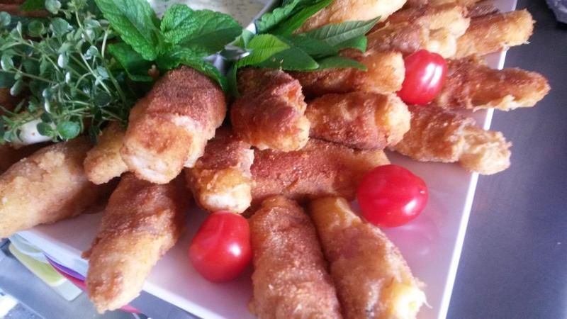 Ein weißer Teller mit frittiertem Essen und Tomaten auf einem Tisch.