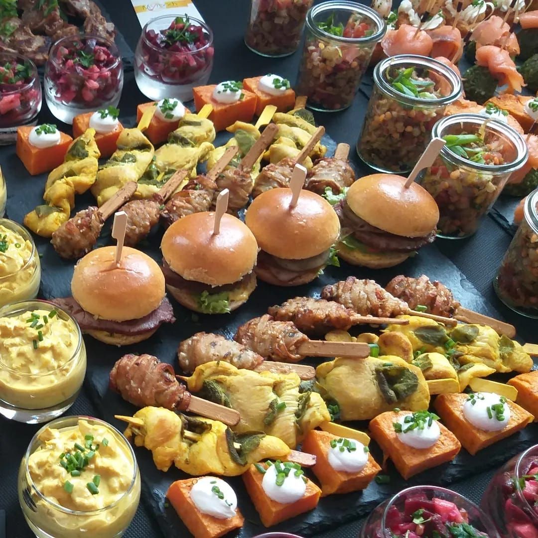 Ein Tisch mit einer Auswahl an Speisen, darunter Hamburger und Vorspeisen