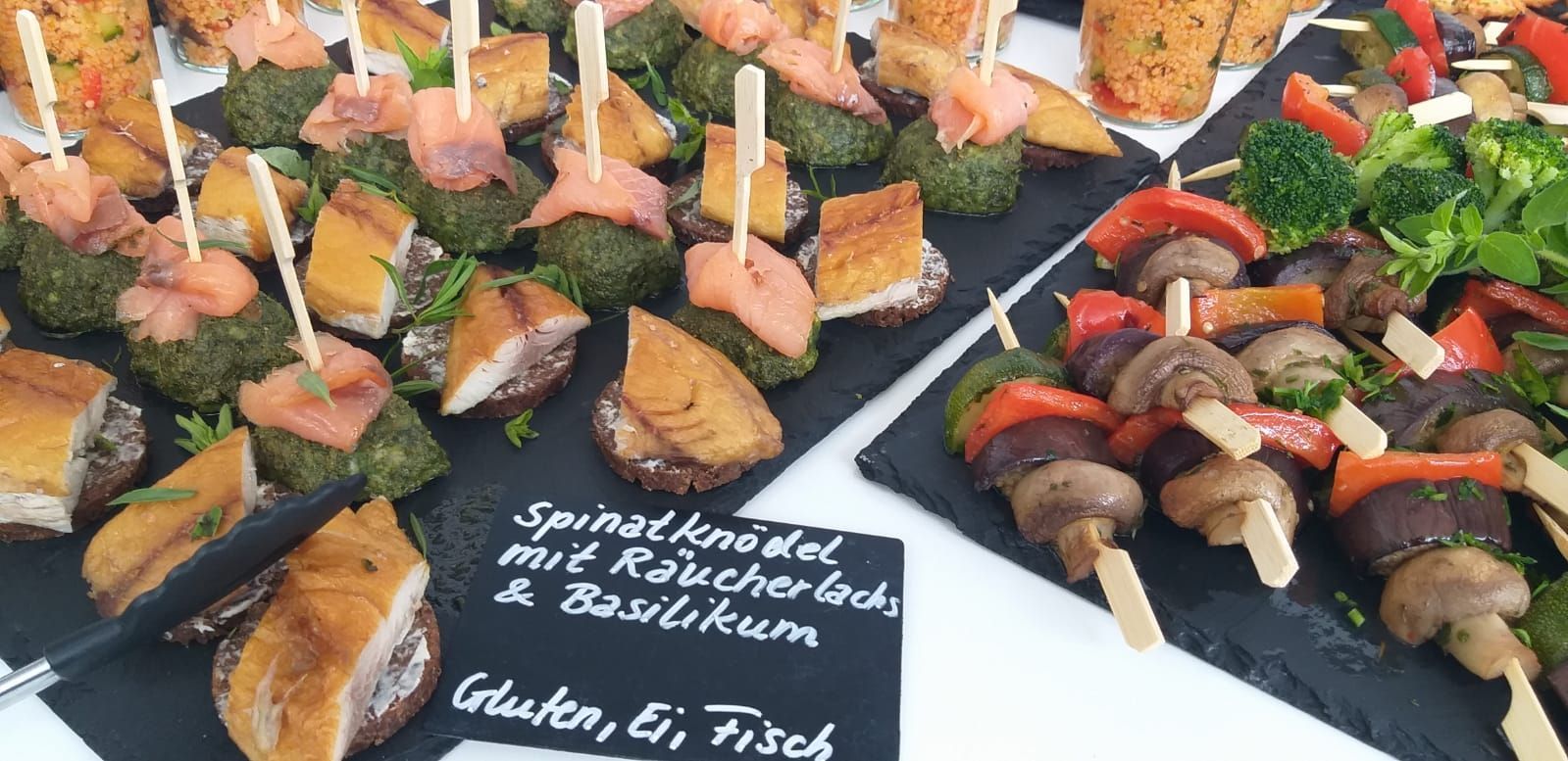 Ein Tisch mit einer Auswahl an Speisen, darunter Spieße und Vorspeisen.