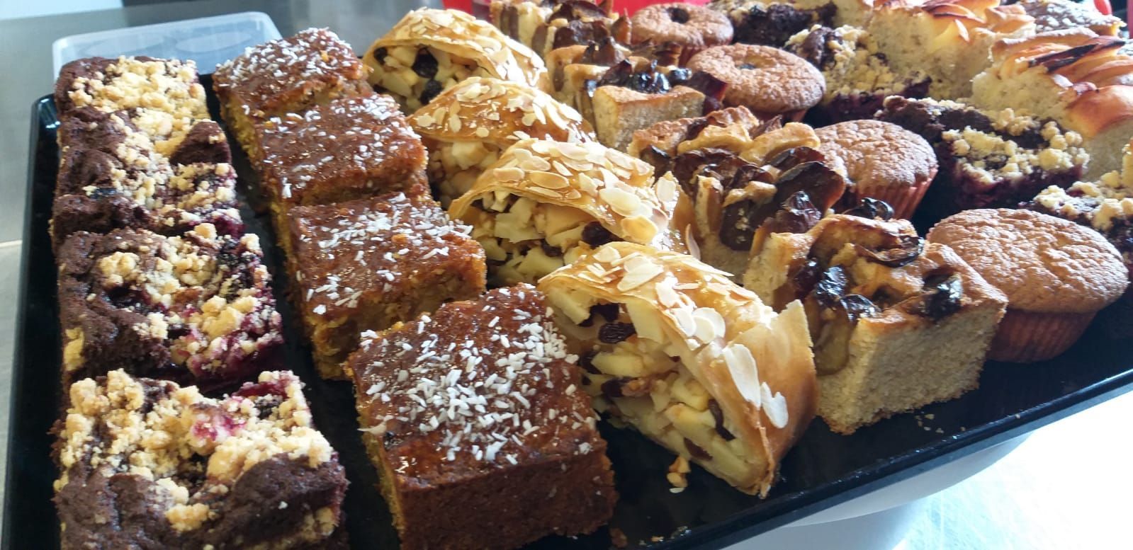 Ein schwarzes Tablett mit verschiedenen Desserts, darunter Brownies und Muffins.