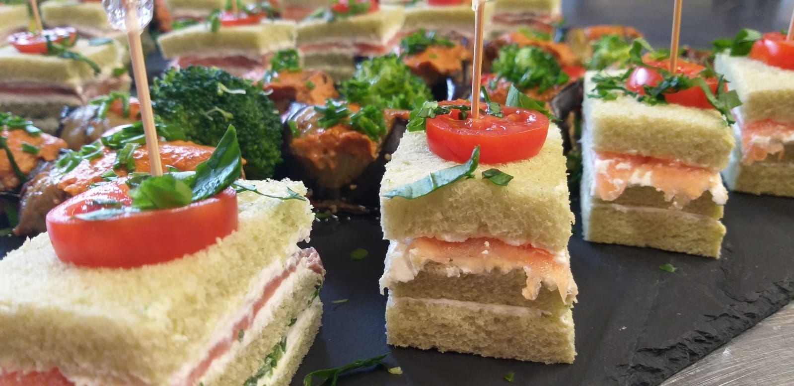 Ein Tablett mit Sandwiches und Tomaten darauf auf einem Tisch.