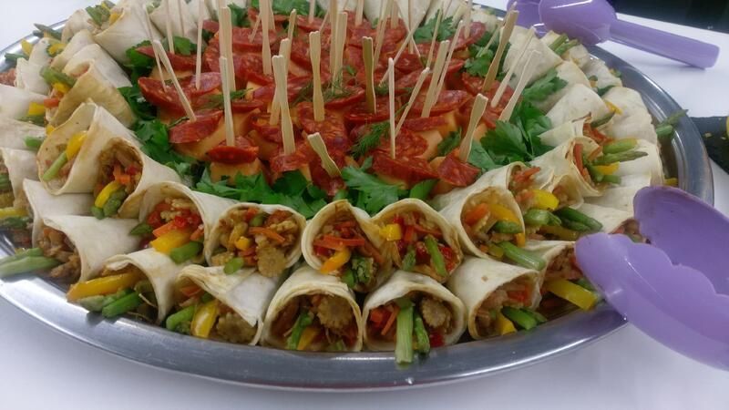 Ein Teller mit Essen, Tortilla-Wraps und Gemüse auf Zahnstochern auf einem Tisch.
