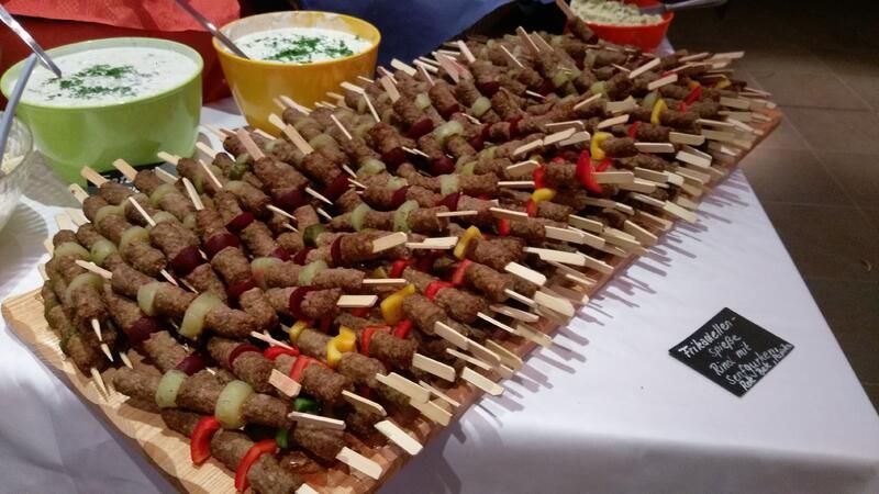 Ein Holztablett gefüllt mit Fleischbällchen und Gemüse auf Spießen.