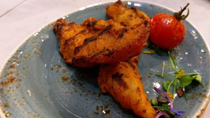 Eine Nahaufnahme eines Tellers mit Essen und einer Tomate auf einem Tisch.