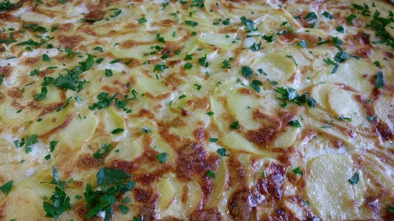 Eine Nahaufnahme einer Pizza mit Kartoffeln und Käse auf einem Tisch.