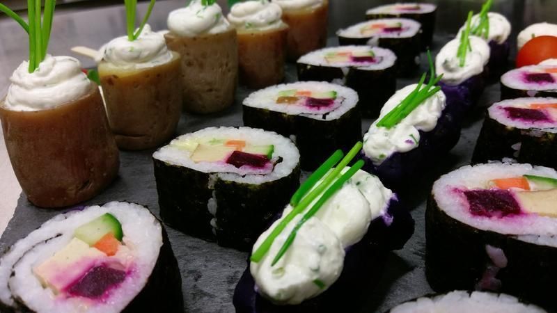 Ein Tisch, bedeckt mit einer Auswahl an Sushi-Rollen und Cupcakes.