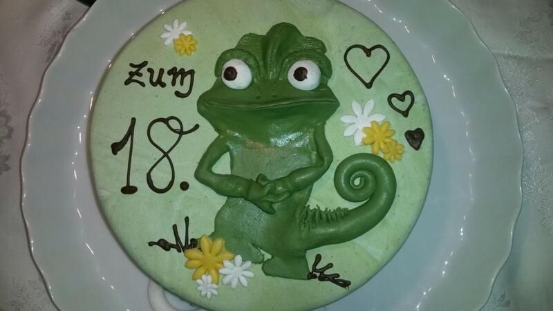 Eine Geburtstagstorte mit einem Chamäleon darauf und dem Datum 18