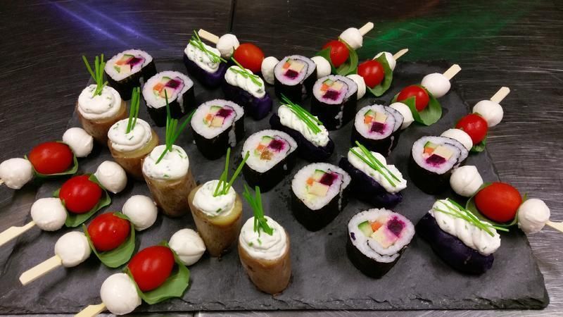 Ein Tablett mit Sushi und Gemüsespießen auf einem Tisch.