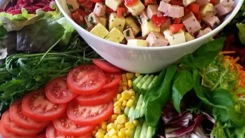 Ein Salat mit Tomaten, Mais und anderem Gemüse in einer Schüssel.