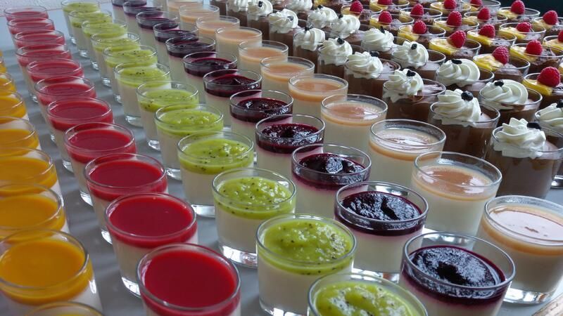 Eine Reihe von Schnapsgläsern, gefüllt mit verschiedenen Dessertsorten.