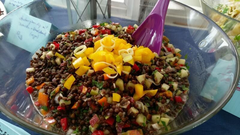 Eine Schüssel mit Essen und einem violetten Löffel darin auf einem Tisch.