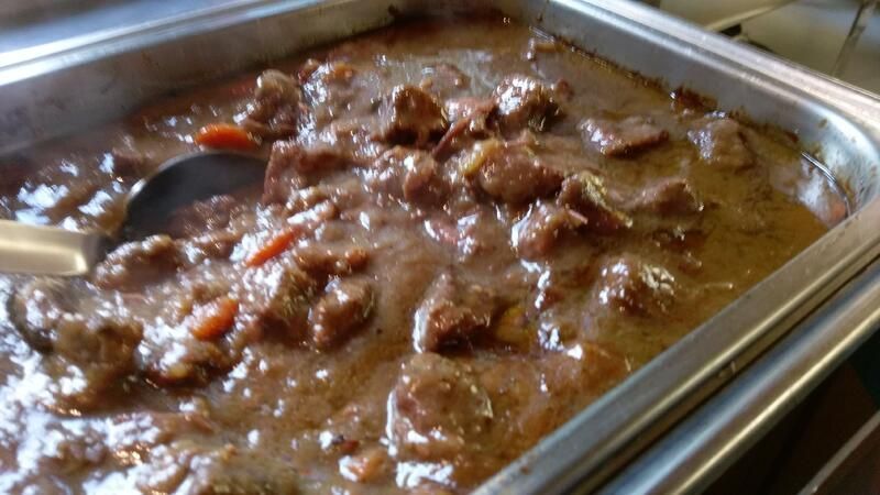 Ein Tablett mit Eintopf und einem Löffel darin.