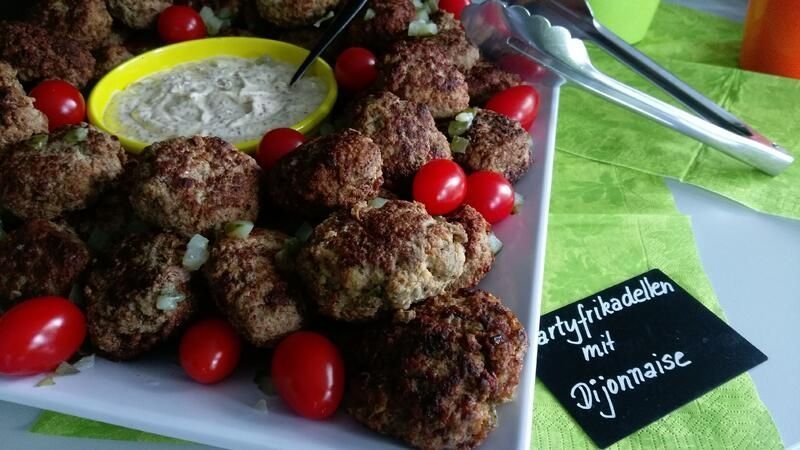 Ein Teller mit Fleischbällchen und Tomaten mit Dip-Sauce auf einem Tisch.