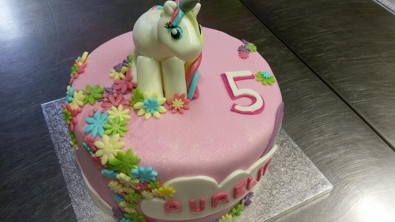 Eine rosa Geburtstagstorte mit einem Einhorn darauf.