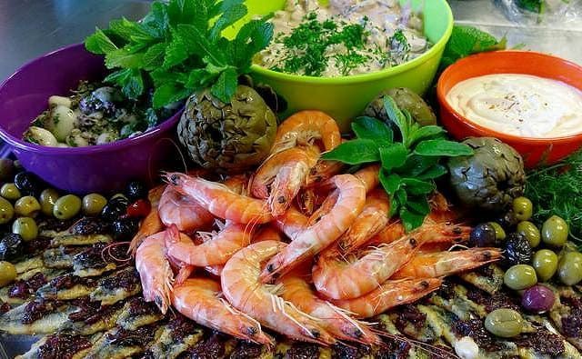 Ein Teller mit Garnelen, Oliven, Artischocken und anderem Gemüse.