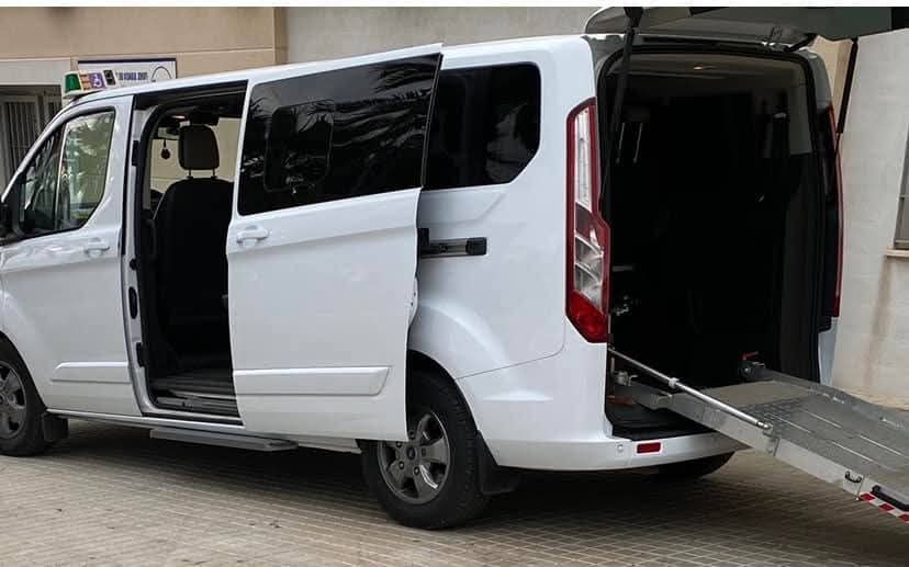 Furgoneta blanca con rampas laterales y traseras desplegadas, lo que demuestra su accesibilidad para sillas de ruedas.