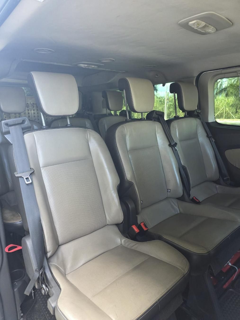 Interior de una furgoneta de tres filas de asientos con tapicería beige y detalles oscuros