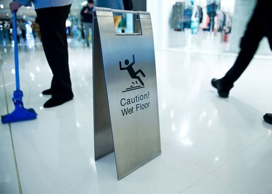Hay un cartel de precaución de piso mojado en el piso de un centro comercial.