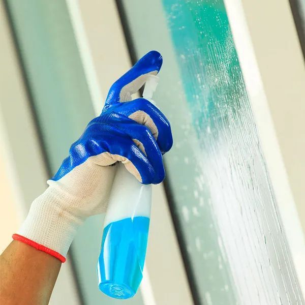 Una persona que lleva guantes azules sostiene una botella de spray.