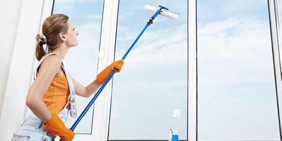 Una mujer está limpiando una ventana con un trapeador.