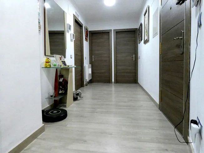 Un pasillo con suelos de madera y un espejo en la pared.