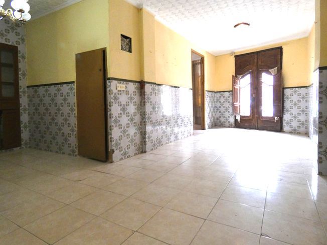 Un pasillo vacío con una lámpara de araña colgando del techo.