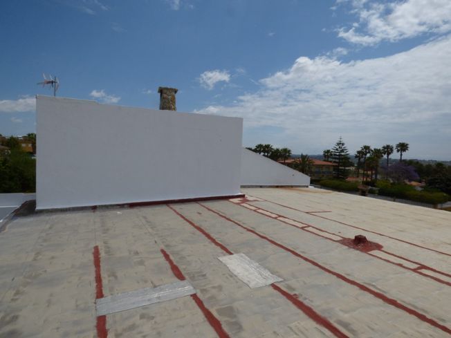 Un techo blanco con rayas rojas y un árbol al fondo.