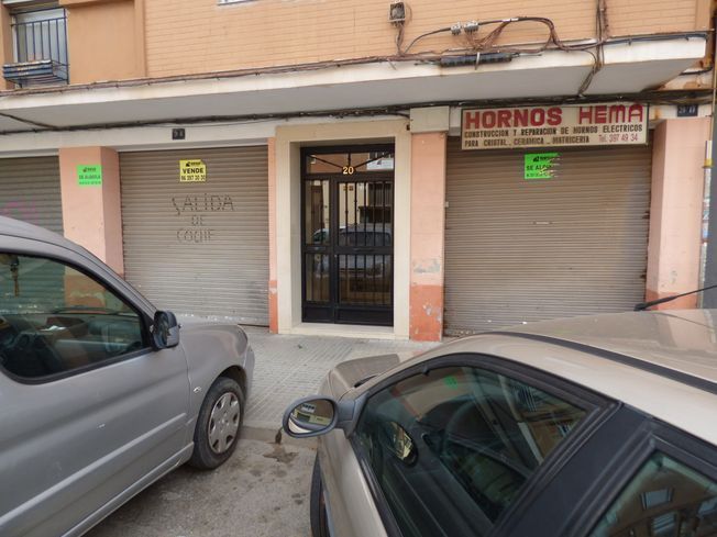 Un coche está aparcado delante de un edificio con un cartel que dice 'alquiler'.