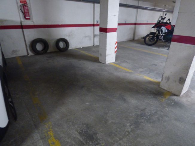 Un coche blanco está aparcado en un aparcamiento.