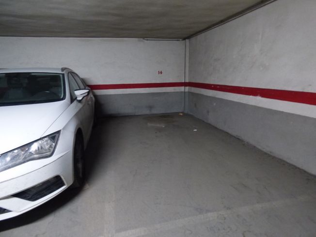 Un coche blanco está aparcado en un aparcamiento.