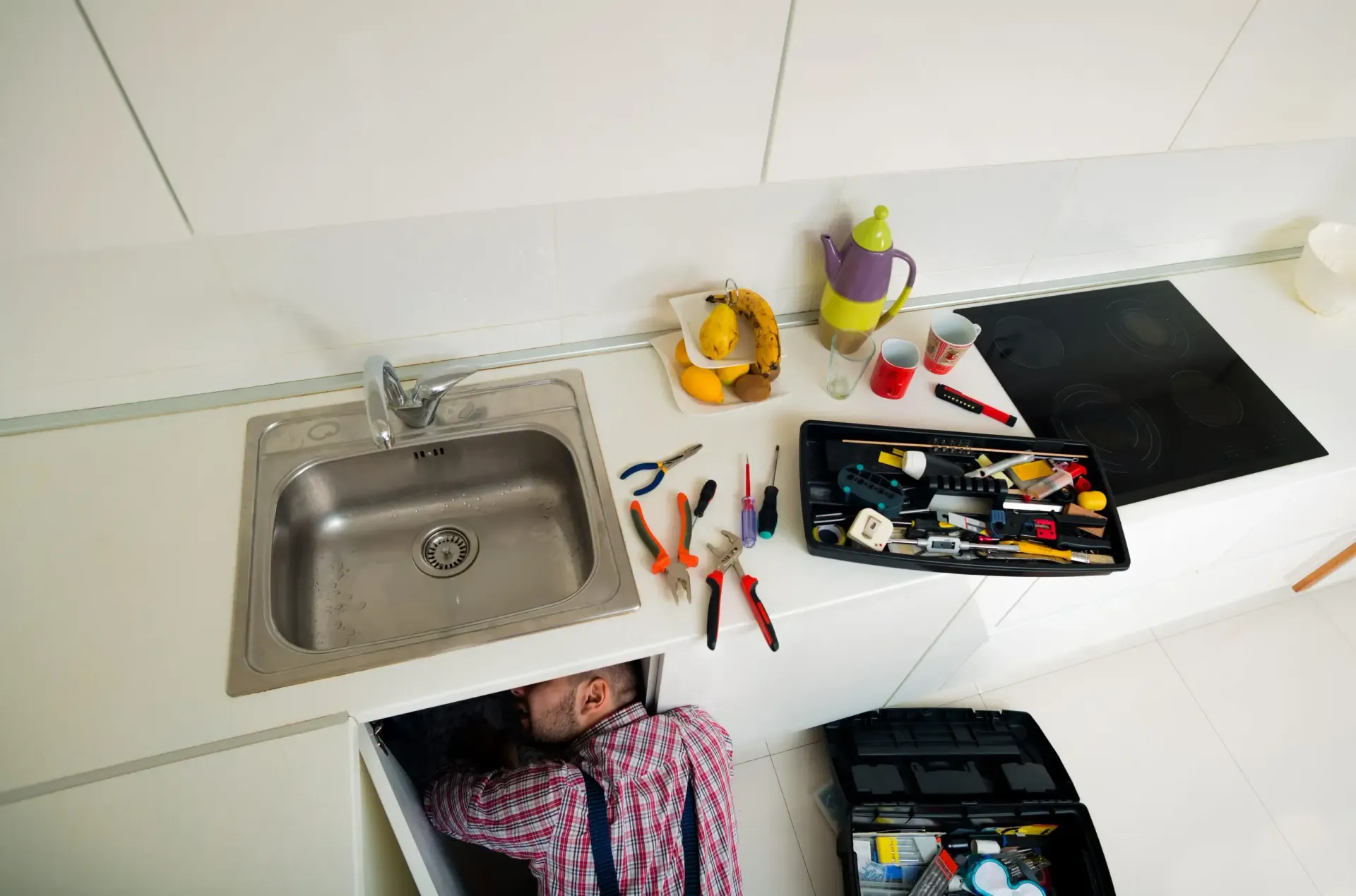 Encimera de cocina con fregadero y utensilios esparcidos junto a una caja de herramientas 