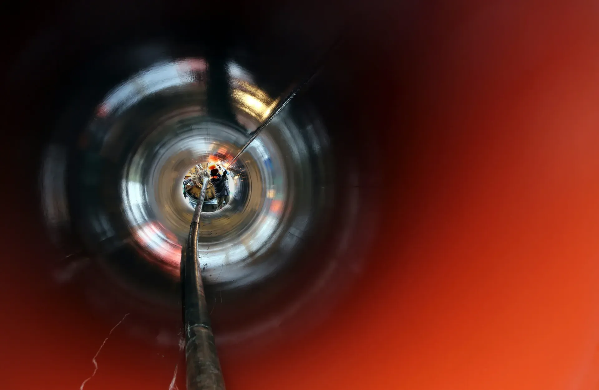 Vista hacia abajo de un tubo de metal con un interior circular rojo y plateado