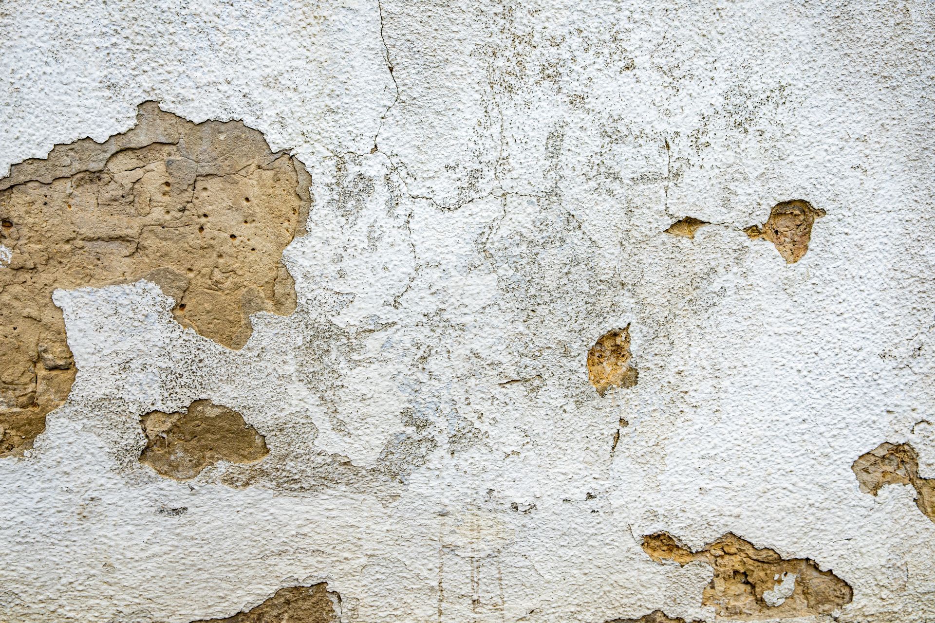 Mur extérieur avec un enduit abîmé et des fissures