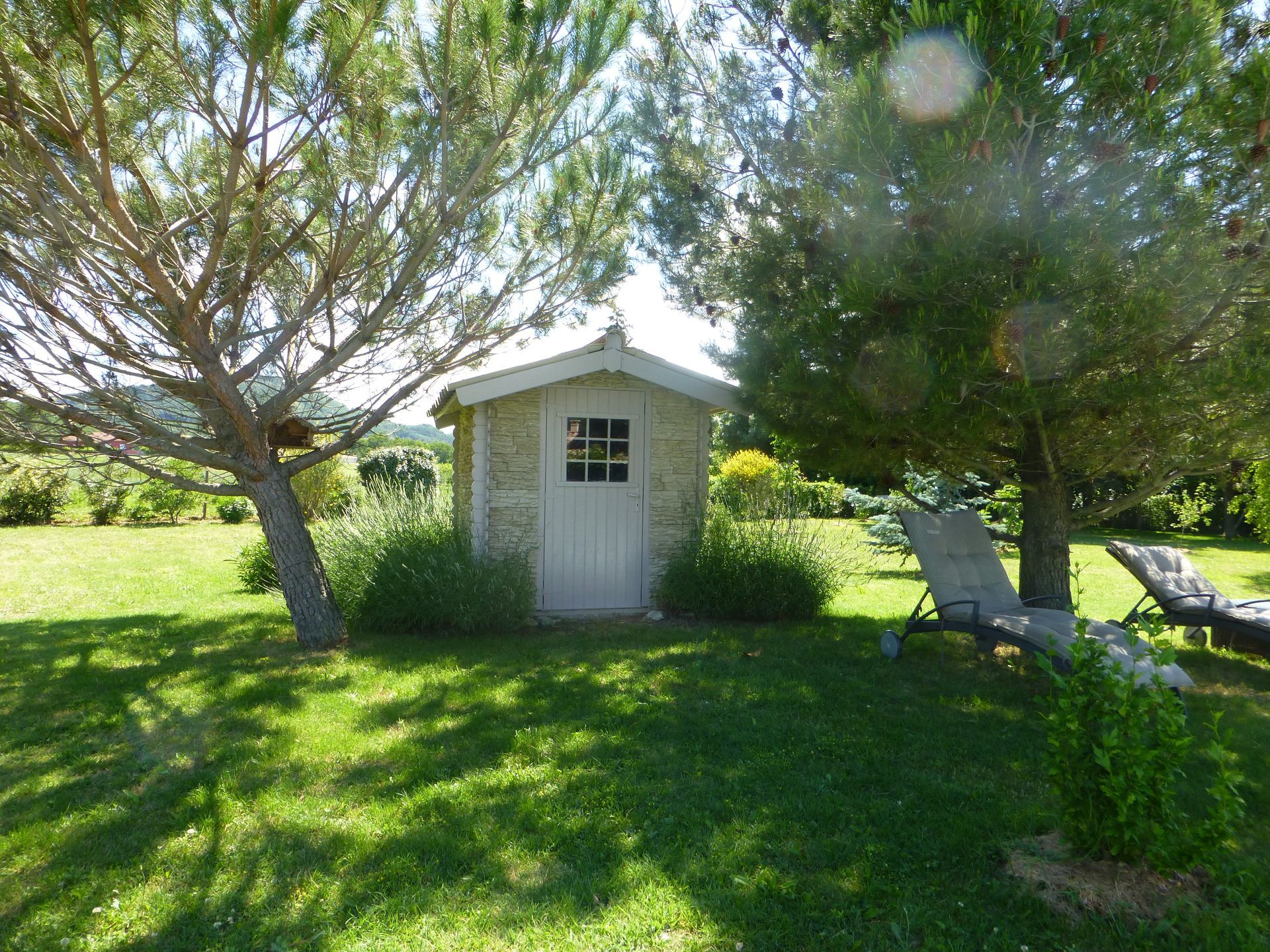 Chalet en bois recouvert de pierres de parement dans un jardin