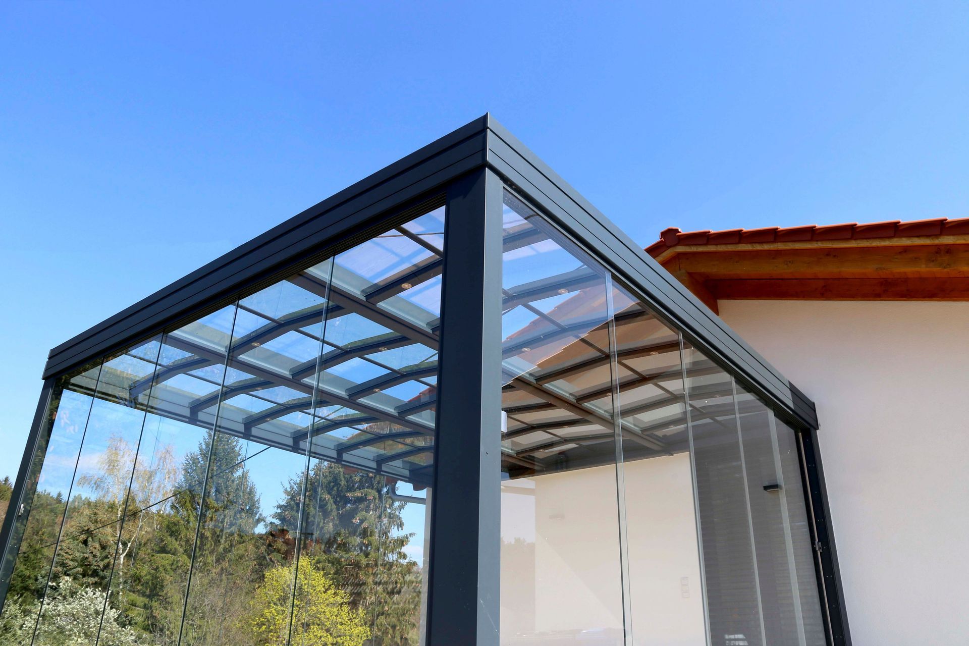 Ein Haus mit einer Glaspergola an der Seite.