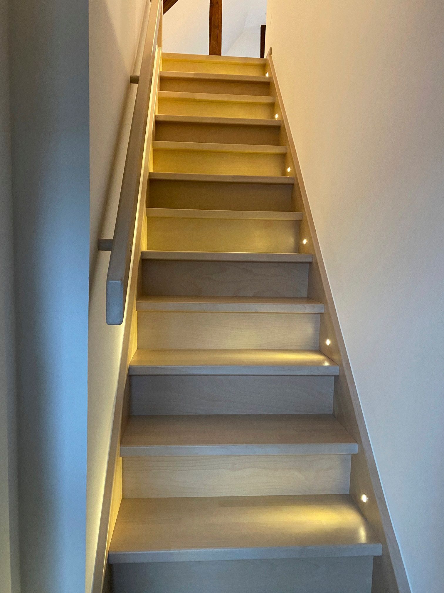 Eine Treppe, die in den zweiten Stock führt, mit Beleuchtung auf den Stufen.