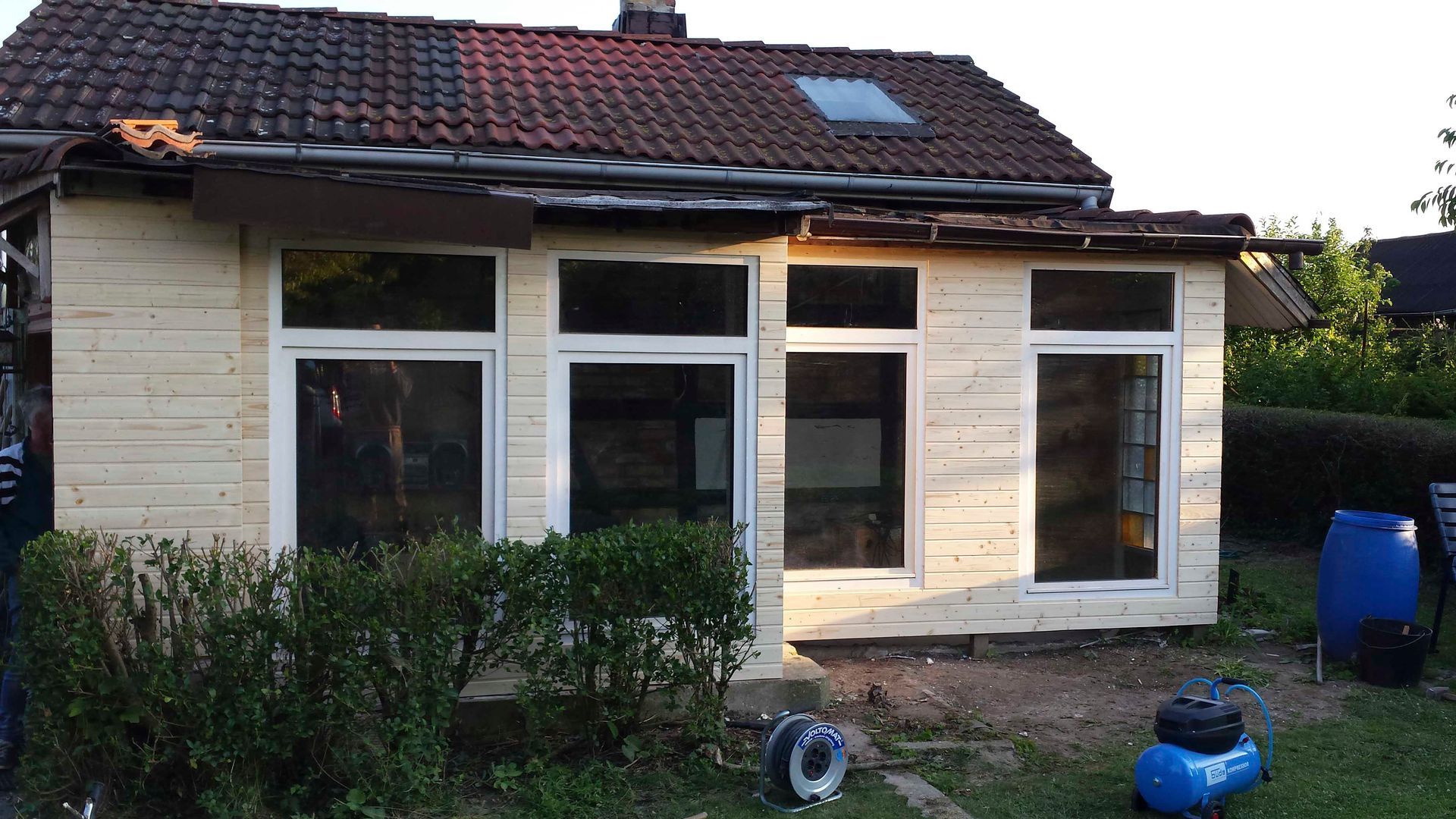 Ein kleines weißes Haus mit einem blauen Luftkompressor davor