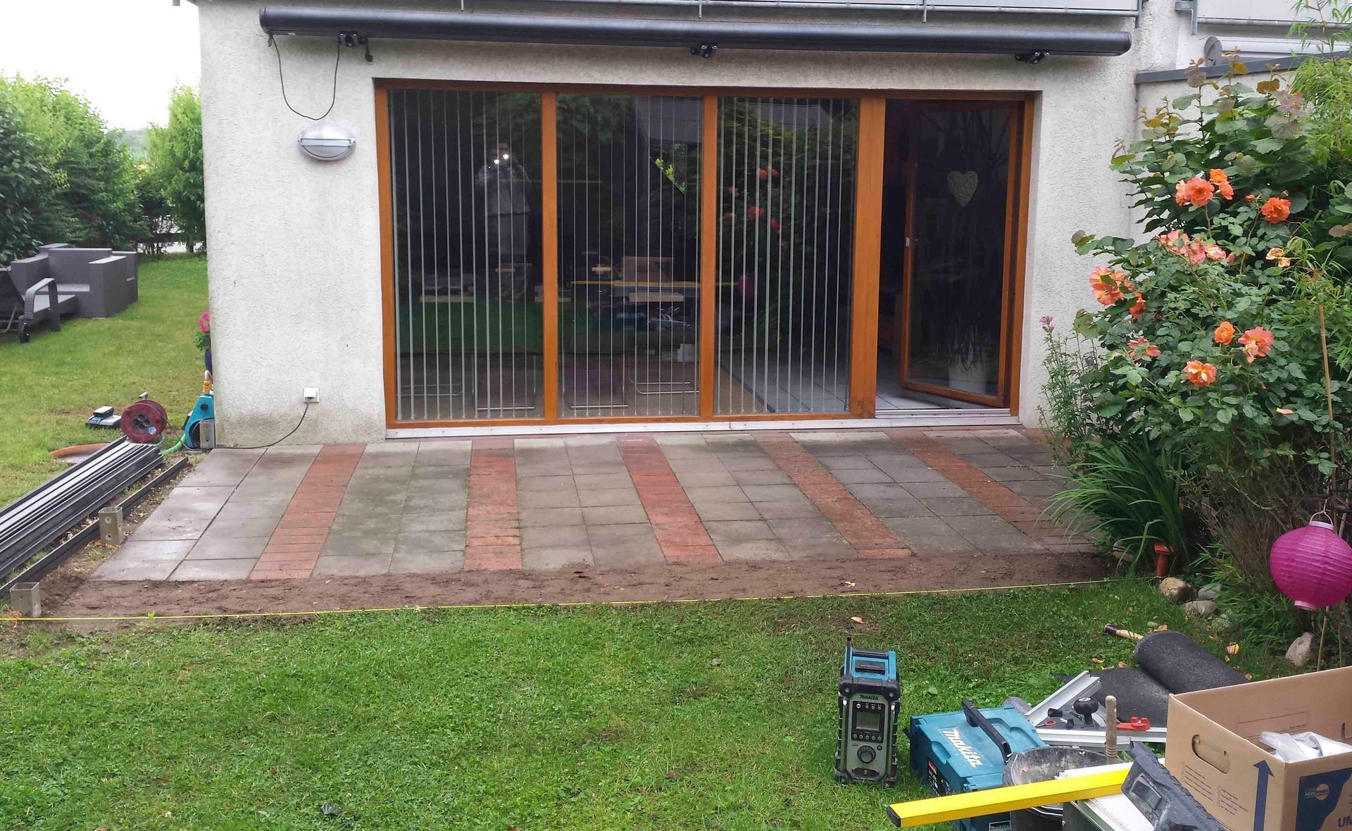 Im Hinterhof eines Hauses gibt es eine Terrasse mit Glasschiebetüren.
