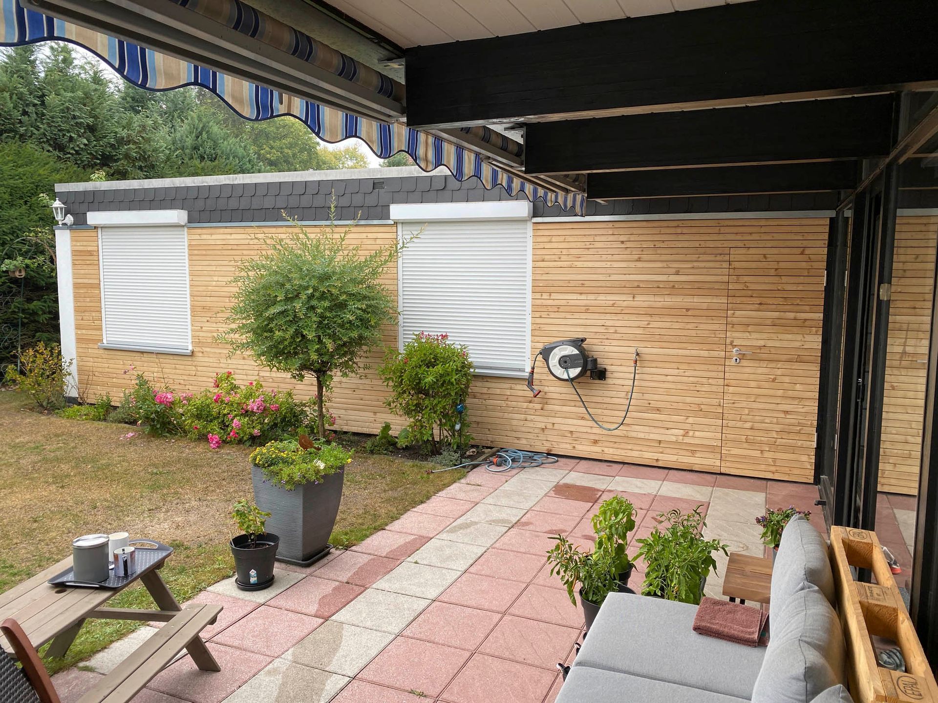 Eine Terrasse mit einer Couch und einem Picknicktisch vor einem Haus.