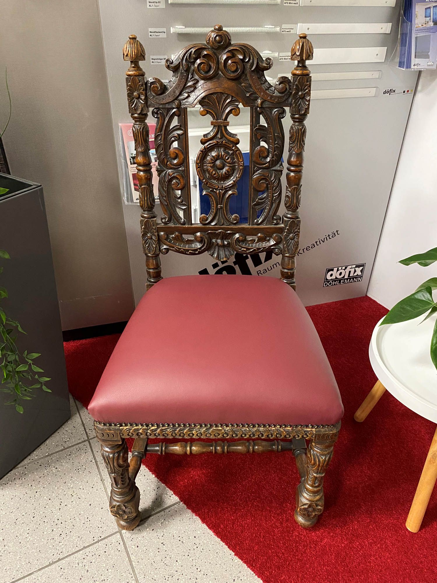 Ein Stuhl mit einem roten Kissen steht auf einem roten Teppich neben einem Tisch.