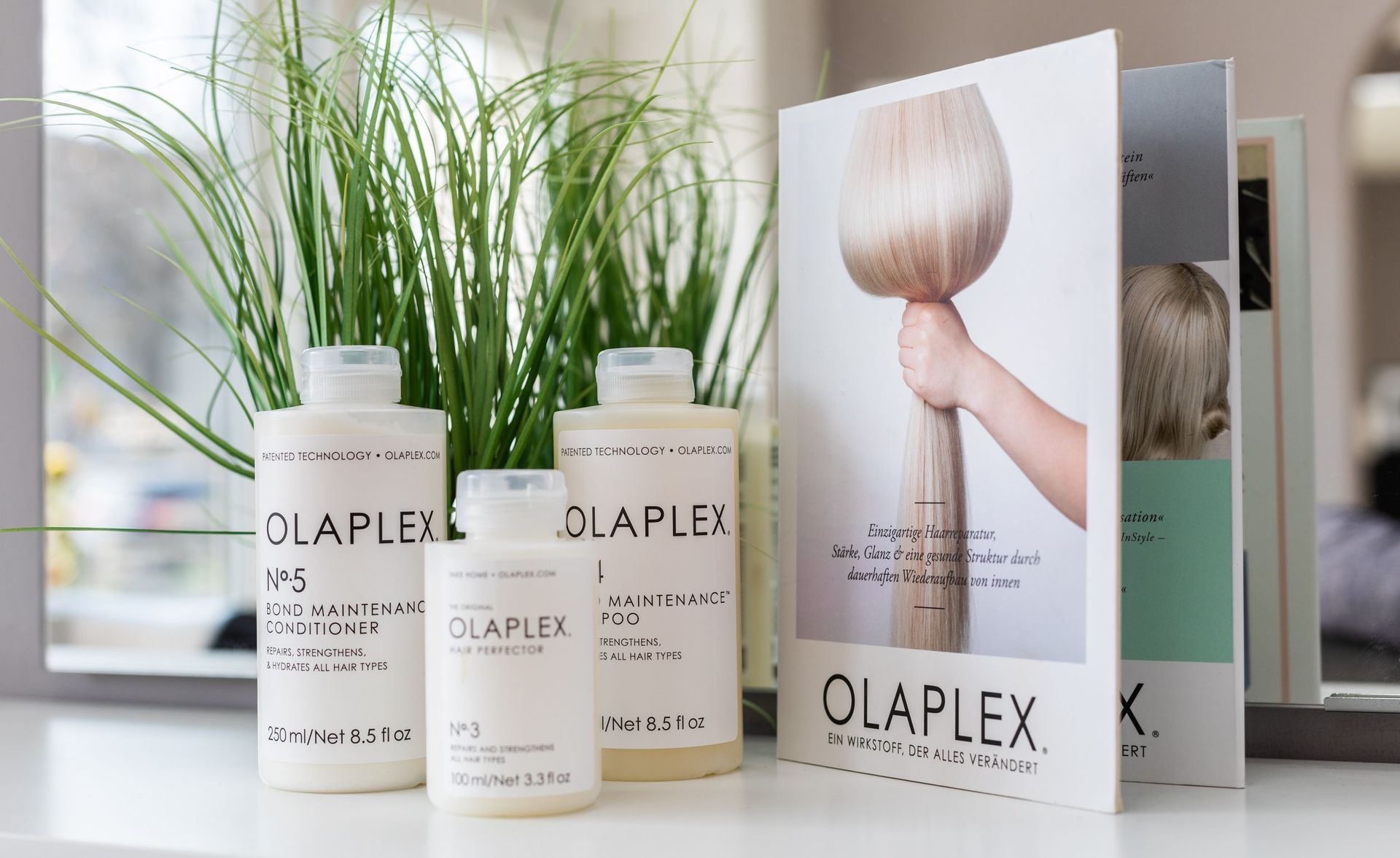 Auf einem Tisch stehen drei Flaschen Olaplex-Haarpflegeprodukte.